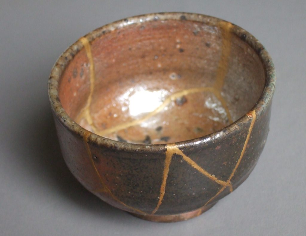 le kintsugi: un bol en céramique japonaise brisée et réparée avec de la laque saupoudrée de poudre d'or.